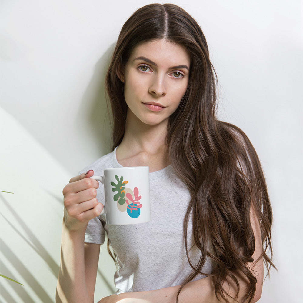 The model holding a White mug featuring dual-tone abstract botanical design, stylish modern drinkware. 