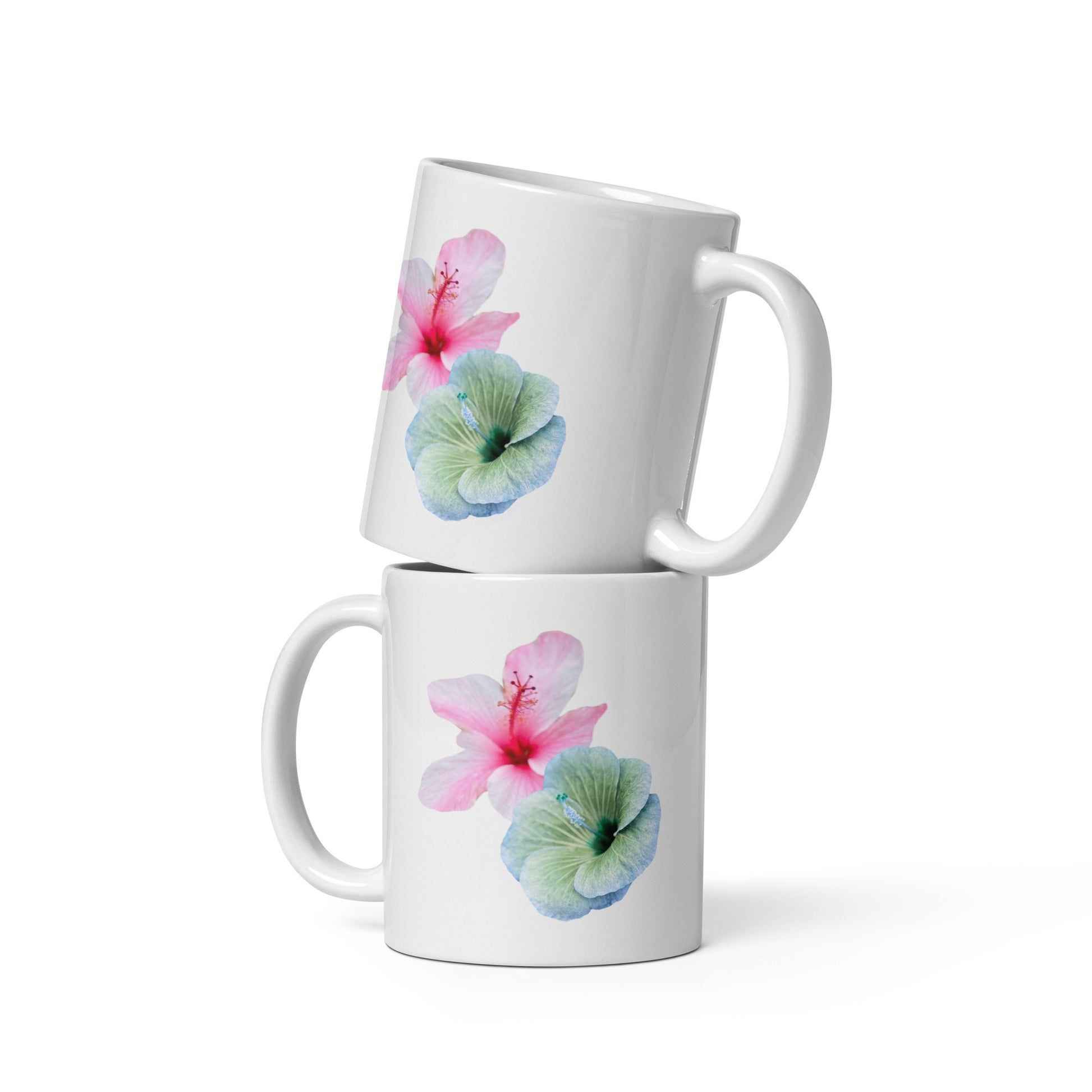 White ceramic mug with soft pink and blue-green hibiscus flowers, floral coffee cup.