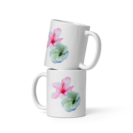 White ceramic mug with soft pink and blue-green hibiscus flowers, floral coffee cup.