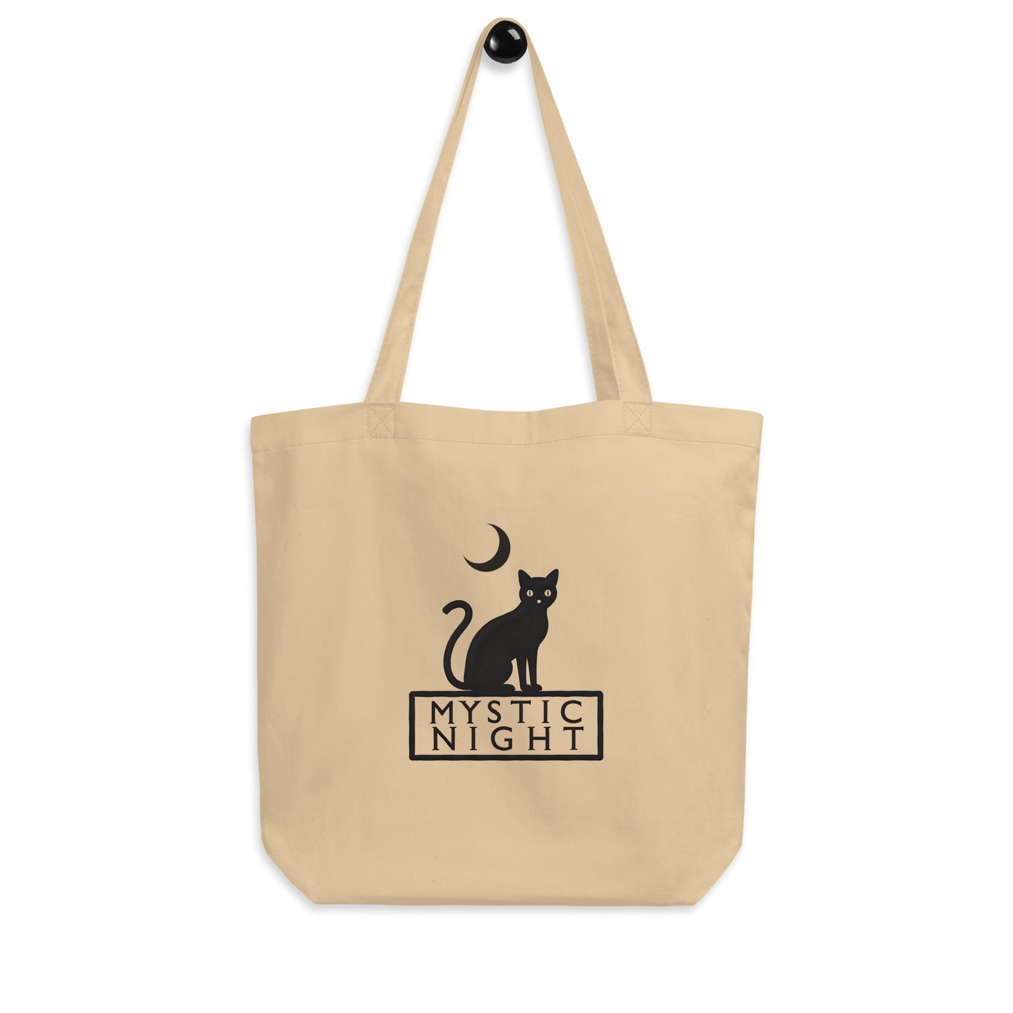 Minimalist oyster color tote bag featuring a black cat sitting under a crescent moon with the text “Mystic Night”.
